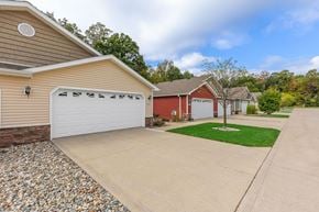 Grand Rapids apartment for rent - A house with a red garage door is surrounded by a gravel driveway and a grassy area.