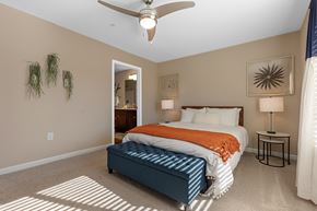 Charlotte apartment for rent - A bedroom with a bed, a ceiling fan, and a nightstand with a lamp.