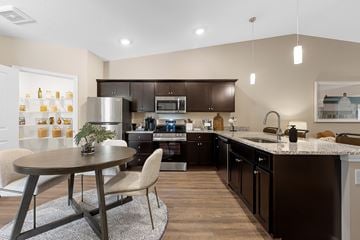 Cincinnati apartment for rent - A modern kitchen with dark brown cabinets and a round table with two chairs.