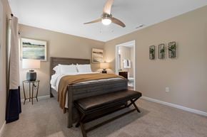 Cincinnati apartment for rent - A bedroom with a bed, bench, and a ceiling fan.