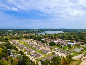 Commerce Twp apartment for rent - A bird's eye view of a residential area with houses, trees, and a body of water.