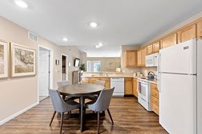 Commerce Twp apartment for rent - A kitchen with a table and chairs in the foreground and a refrigerator on the right.