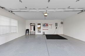 Commerce Twp apartment for rent - A spacious garage with a black mat on the floor and a red sign on the door.