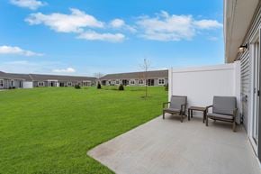 Crystal Lake apartment for rent - A row of houses with a lawn in front and two chairs on a concrete walkway.