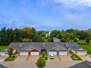 Lansing apartment for rent - A large house with a red garage door is surrounded by a driveway and trees.