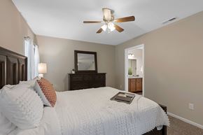 Lansing apartment for rent - A bedroom with a bed, dresser, mirror, and a ceiling fan.