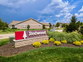 Fairborn apartment for rent - A sign for Redwood Apartment Homes is in front of a building.