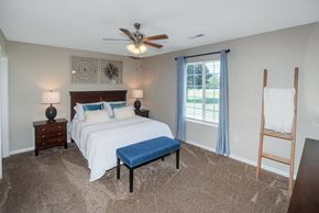 Findlay apartment for rent - A bedroom with a bed, nightstand, and a window with a view of the outside.