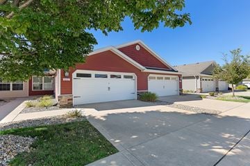 Fort Wayne apartment for rent - A red house with a white garage door is surrounded by a gravel area and a grassy patch.