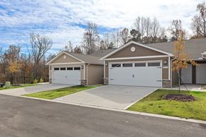 Fox River Grove apartment for rent - A two-car garage with a brown roof and white doors is surrounded by a concrete driveway and a grassy area.