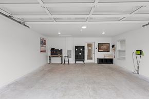 Fox River Grove apartment for rent - A spacious room with a white ceiling and walls, containing a workbench, a black cabinet, and a green and black object on the floor.
