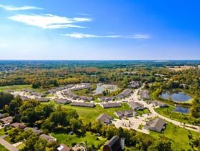 Grand Blanc Township apartment for rent - A bird's eye view of a residential area with houses, trees, and a pond.