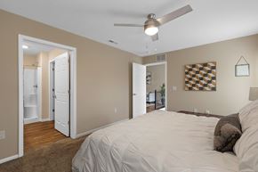 Grand Rapids apartment for rent - A bedroom with a bed, a ceiling fan, and a checkerboard patterned picture on the wall.