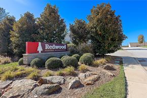 Greer apartment for rent - A sign for Redwood Apartment Neighborhoods is displayed in front of some trees.