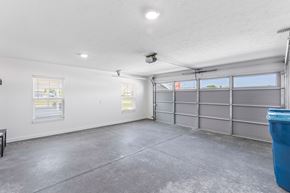 Grove City apartment for rent - A spacious garage with a concrete floor and a grey garage door.