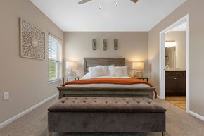 Holt apartment for rent - A bedroom with a large bed and a bench in front of it.
