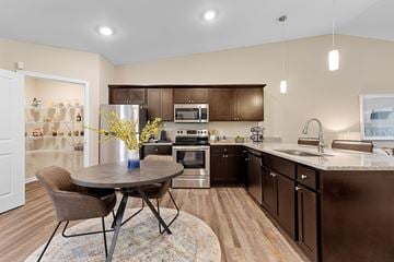 Lafayette apartment for rent - A kitchen with brown cabinets and a round table with chairs.