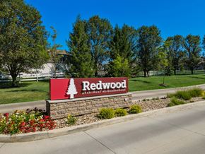 Marysville apartment for rent - A sign for Redwood Apartment Neighborhoods is displayed in front of a grassy area.