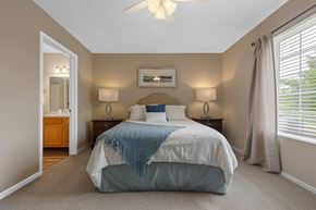 Maumee apartment for rent - A bedroom with a bed, two lamps, and a ceiling fan.