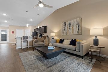 Maumee apartment for rent - A modern living room with a grey couch, a coffee table, and a painting on the wall.