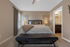 Maumee apartment for rent - A bedroom with a large bed and a black bench.