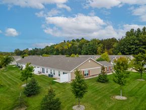 Midland apartment for rent - A house with a grey roof and white walls is surrounded by a green lawn and trees.