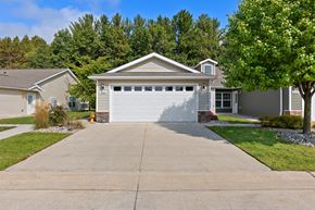Midland apartment for rent - A house with a grey garage door is surrounded by greenery.
