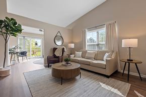 Midland apartment for rent - A living room with a white couch, a wooden coffee table, and a large window with white curtains.