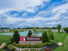 Groveport apartment for rent - A sign for Redwood Apartment Neighborhood sits in front of a grassy area with a lake in the background.