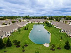 Perrysburg apartment for rent - A large swimming pool is surrounded by grass and trees in a residential area.