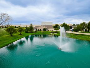 Perrysburg apartment for rent - A fountain in the middle of a pond in front of a building.