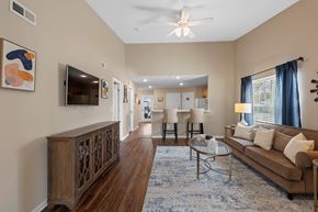 Perrysburg apartment for rent - A living room with a brown couch, a glass coffee table, and a ceiling fan.