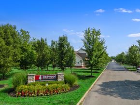 Pickerington apartment for rent - A street view of Redwood with a sign, trees, and a house.