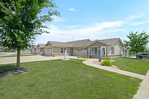 Plainfield apartment for rent - A building with a sign that says "Sunrise Senior Living" is surrounded by a grassy area and trees.