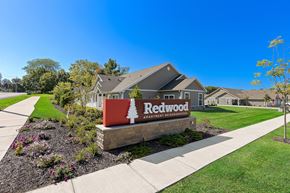Portage apartment for rent - A sign for Redwood Apartment is in front of a building.