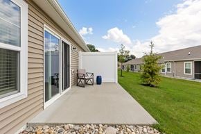 Batavia apartment for rent - A patio with a table and chairs is surrounded by a grassy area and other houses.