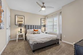 Reynoldsburg apartment for rent - A bedroom with a bed, a ceiling fan, and a small table with a lamp on it.