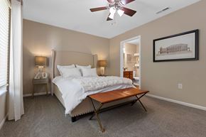 Shelby Twp apartment for rent - A bedroom with a bed, a bench, and a painting on the wall.