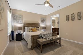 Simpsonville apartment for rent - A bedroom with a bed, bench, and decorative wall art.