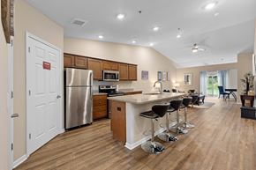 Temperance apartment for rent - A kitchen with a refrigerator, stove, and bar stools.