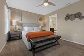 Kalamazoo apartment for rent - A bedroom with a bed, a bench, and a ceiling fan.