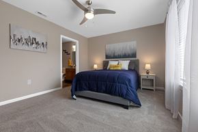 Tipp City apartment for rent - A bedroom with a bed, nightstand, and a painting on the wall.