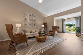 Troy apartment for rent - A living room with a grey sofa, a wooden coffee table, and a large window with a view of the outdoors.