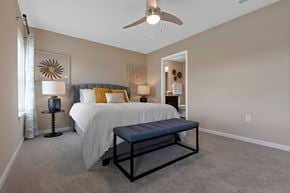 Troy apartment for rent - A bedroom with a bed, a bench, and a ceiling fan.