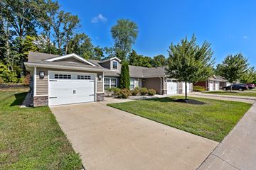 Union Township apartment for rent - A residential house with a white garage door is surrounded by a well-maintained lawn and a clear blue sky.