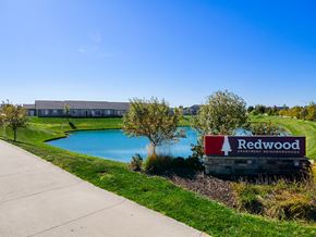 Waukee apartment for rent - A sign for Redwood Apartment Residences is in front of a building and a pool.