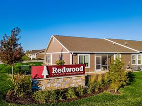 Waukee apartment for rent - A sign for Redwood Apartment Homes is in front of a building.