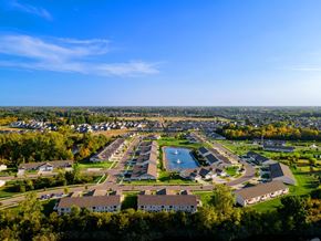 Ypsilanti apartment for rent - A bird's eye view of a residential area with houses, a swimming pool, and a green lawn.