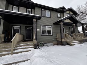 Edmonton apartment for rent - A house with a grey exterior and a snow-covered ground in front.