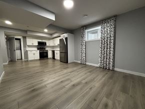 Edmonton apartment for rent - A kitchen with wooden floors and a window with curtains.